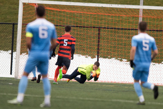 Syracuse goalie Hendrik Hilpert hauls in a ball. He made eight saves in the contest. SU defender Louis Cross looks on.