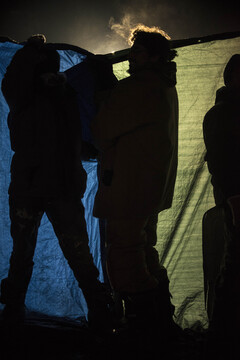 Water protectors near the barricade hold up tarps to protect other people from the water cannons that were causing hypothermia in the freezing cold temperatures.