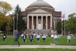 As the scholars sit in their seats for 35 minutes, students walk by and observe the ceremony.